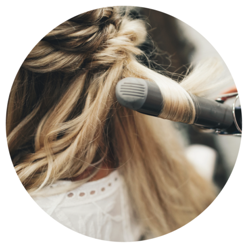 Stylist giving a client a smooth, voluminous blowout with a round brush at Blush Beauty & Co in Ogden